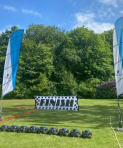 En række fjernstyrede biler på en græsplæne med en mållinje i baggrunden. At køre med Radio Control Cars er en sjov oplevelse for alle. I inddeles på hold, så I kan få en fornemmelse af konkurrence, samarbejde og har det sjovt sammen.