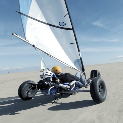 En strandsurfer med en voksen og et barn kører på en endeløs strand.