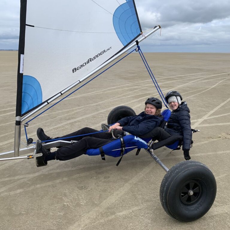 En dobbelt strandsurfer på en flad bred strand.