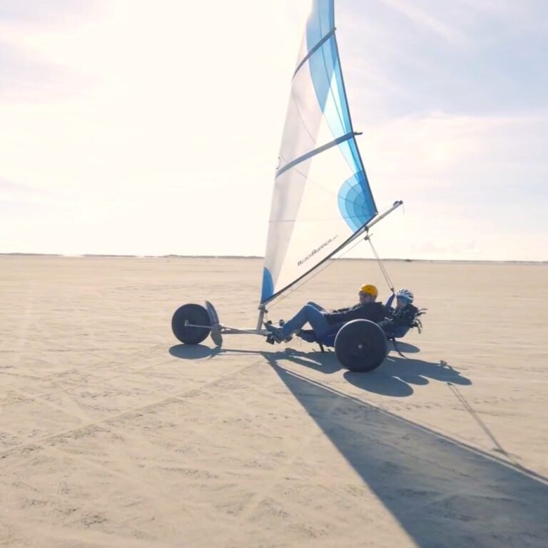 En dobbelt strandsurfer på en flad bred strand.