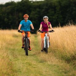 2 cyklister iført cykelhjelm på elektriske cykler på en græssti. Book en tur med Elektriske Bikes til jeres næste firmaevent. Kan arrangeres i hele landet.