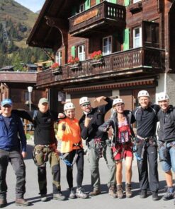 En gruppe mennesker står i en Schweizisk landsby iført hjelme og klatreseler. På firmarejse til Interlaken, Schweitz.