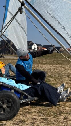 En kvindelig strandsurfer med en orange hjelm bliver vejledt af en instruktør til, hvordan man styrer en lands-/strandsurfer.