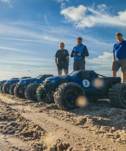 Nærbillede af en række fjernstyrede biler på en strand med blå himmel og sol i baggrunden. At køre med Radio Control Cars er en sjov oplevelse for alle. I inddeles på hold, så I kan få en fornemmelse af konkurrence, samarbejde og har det sjovt sammen.