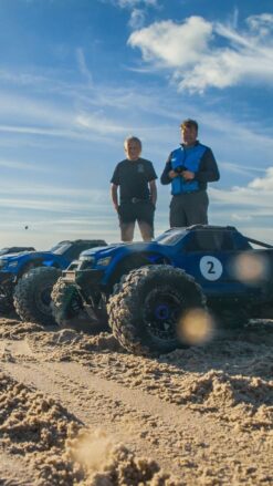Nærbillede af en række fjernstyrede biler på en strand med blå himmel og sol i baggrunden. At køre med Radio Control Cars er en sjov oplevelse for alle. I inddeles på hold, så I kan få en fornemmelse af konkurrence, samarbejde og har det sjovt sammen.
