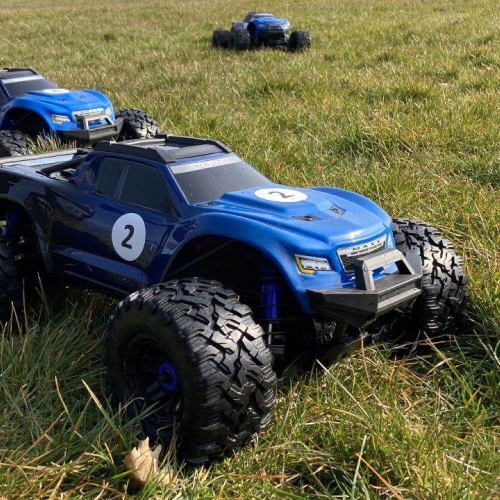 Nærbillede af en fjernstyret bil på en græsplæne. At køre med Radio Control Cars er en sjov oplevelse for alle. I inddeles på hold, så I kan få en fornemmelse af konkurrence, samarbejde og har det sjovt sammen.