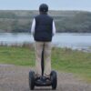 En mand set bagfra kører på Segway på en grussti. Book jeres næste event med os og oplev, hvordan et Segway Event kan løfte teamets samarbejde til nye højder!