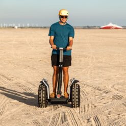 En ung mand kører på Segway på en strand, hvor solen skinner. Book jeres næste event med os og oplev, hvordan et Segway Event kan løfte teamets samarbejde til nye højder!