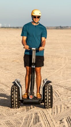 En ung mand kører på Segway på en strand, hvor solen skinner. Book jeres næste event med os og oplev, hvordan et Segway Event kan løfte teamets samarbejde til nye højder!