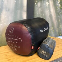 Sovepose fra mærket Nordisk på et træbord sammen med en silkeinderpose - til udlejning hos OurStuff