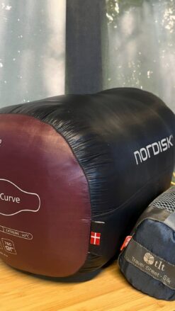 Sovepose fra mærket Nordisk på et træbord sammen med en silkeinderpose - til udlejning hos OurStuff