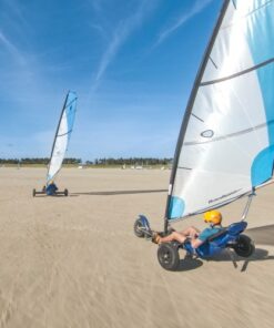 To strandsurfere kører på en flad, bred strand på Rømø på en dag med blå himmel.