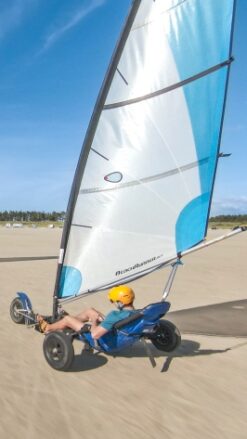 To strandsurfere kører på en flad, bred strand på Rømø på en dag med blå himmel.