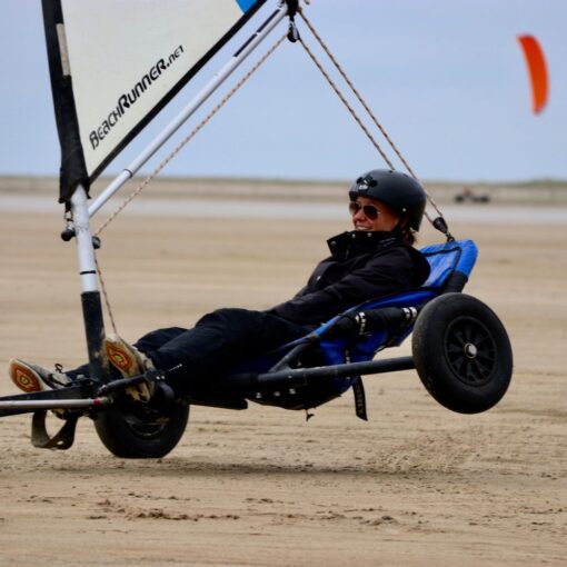 En kvinde sidder i en strandsurfer, der har det ene hjul løftet op i luften.