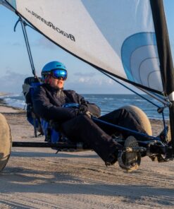En ung mand kører i en strandsurfer. I hans skibriller spejler solen sig.