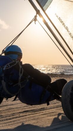 En strandsurfer kører langs stranden ved solnedgang.