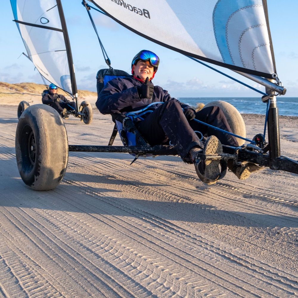 Ung mand i solskin i en strandsurfer. Prøv strandsurfing på Rømø til jeres næste event - det er helt sikkert og trygt for alle.